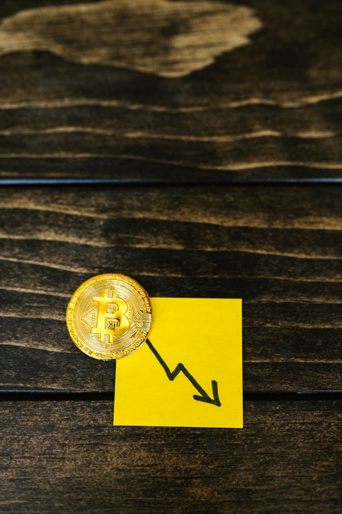 Bitcoin coin with a downward trend graph on a yellow sticky note, symbolizing market decline.